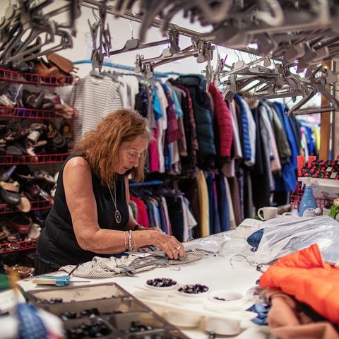 Barbara leaning over a table sorting donations