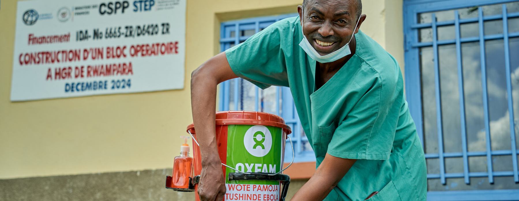 A smiling man in medical clothes setting up an emergency tab in the Democratic Republic of the Congo.