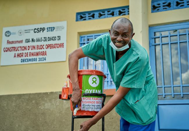 A smiling man in medical clothes setting up an emergency tab in the Democratic Republic of the Congo.
