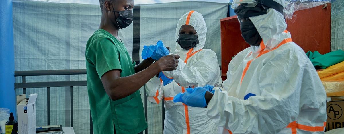 Joseph Kandule assisting team in protective suits with gloves.