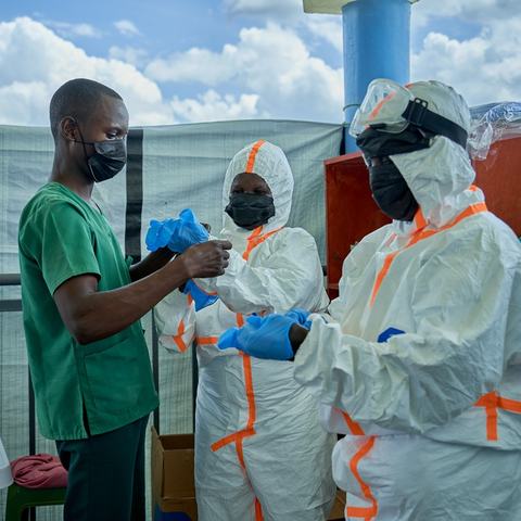 Joseph Kandule assisting team in protective suits with gloves.