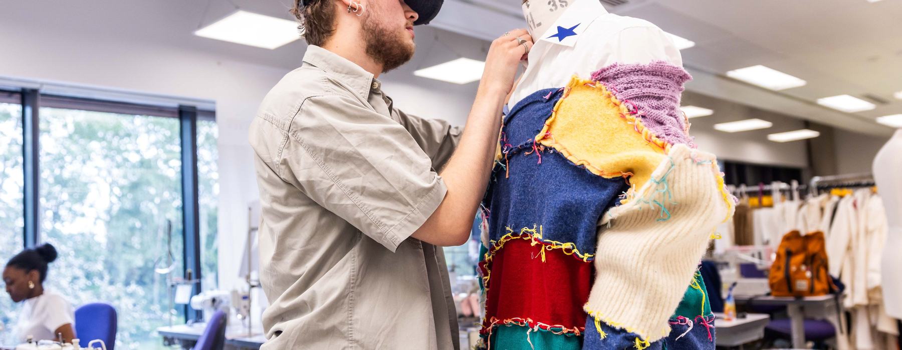 A Leeds Beckett student who is a fashion design student pinning fabric to a mannequin.