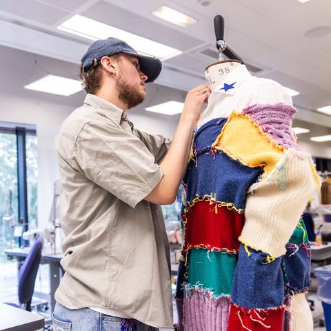 A Leeds Beckett student who is a fashion design student pinning fabric to a mannequin.