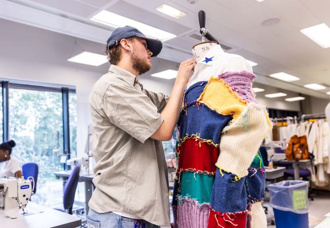 A Leeds Beckett student who is a fashion design student pinning fabric to a mannequin.