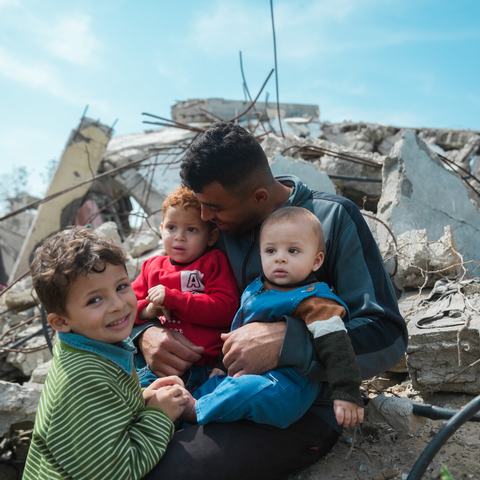 Mohammed sitting atop the rubble of his house with his three children.