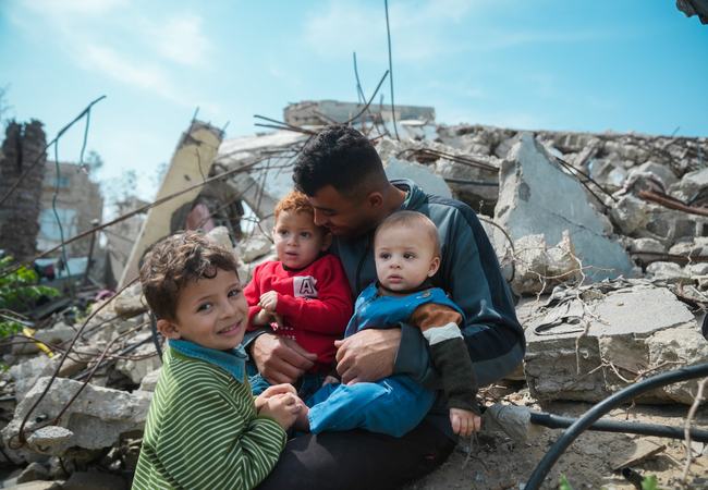 Mohammed sitting atop the rubble of his house with his three children.