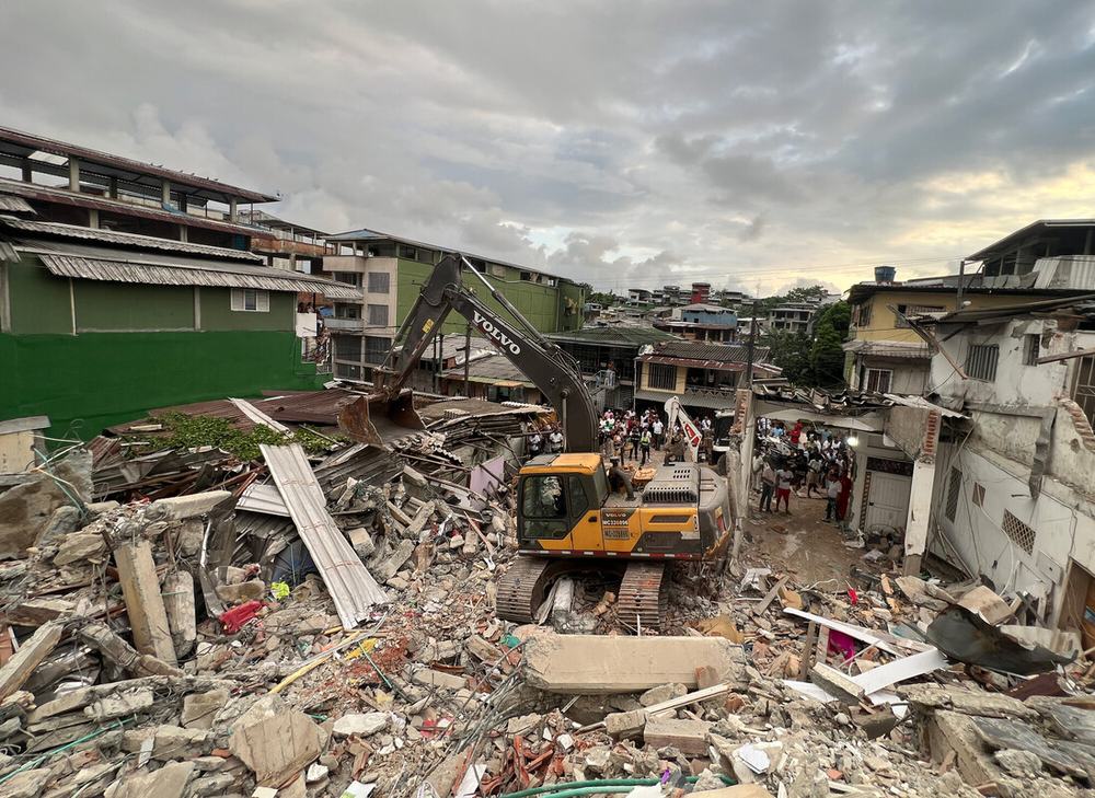 Record of the damage caused by the earthquake, showing collapsed buildings and debris removal operations using heavy machinery. The image demonstrates the scale of the destruction in an urban area of the municipality.