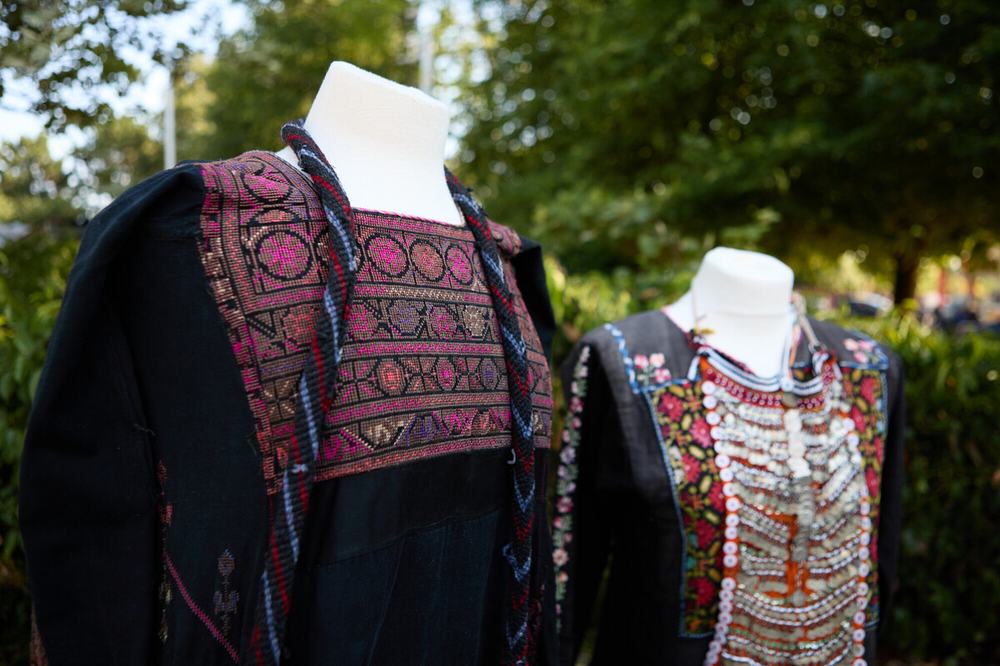 Two traditional Palestinian dresses (thobes) in black fabric with traditional embroidery (tatreez) in pink, blue, yellow and orange threads.