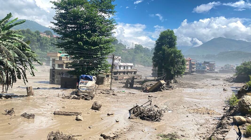 Buildings and trees surrounded by muddy flood water in Nuwakot District, Nepal after the huge flash flood.