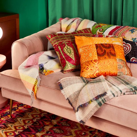 A sofa with plush cushions and warm blankets on it.