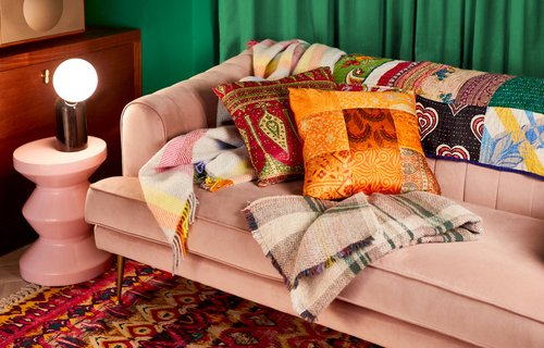 A sofa with plush cushions and warm blankets on it.