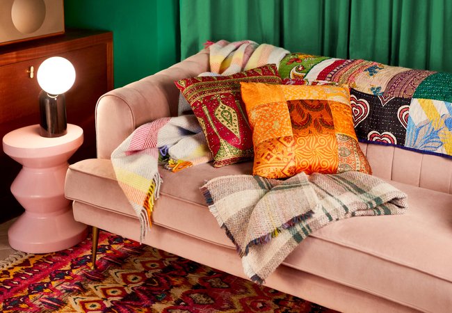 A sofa with plush cushions and warm blankets on it.