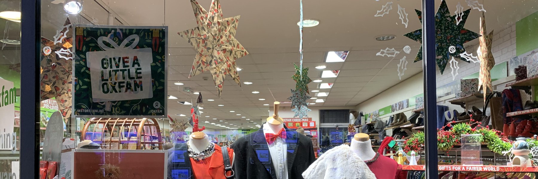 A Christmas window display in an Oxfam shop with large handmade paper stars