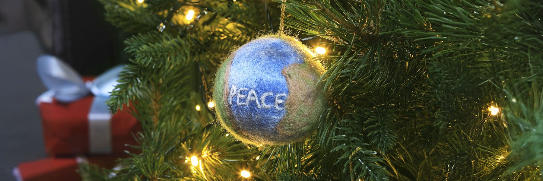 A felt Peace bauble hangs in a Christmas tree