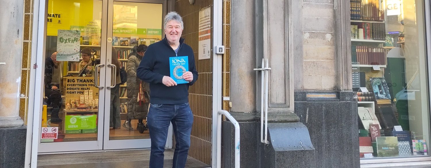 Paul Dixon holding Iona Celtic Art book on the steps of Oxfam Stirling