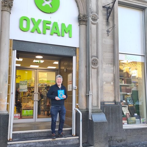 Paul Dixon holding Iona Celtic Art book on the steps of Oxfam Stirling