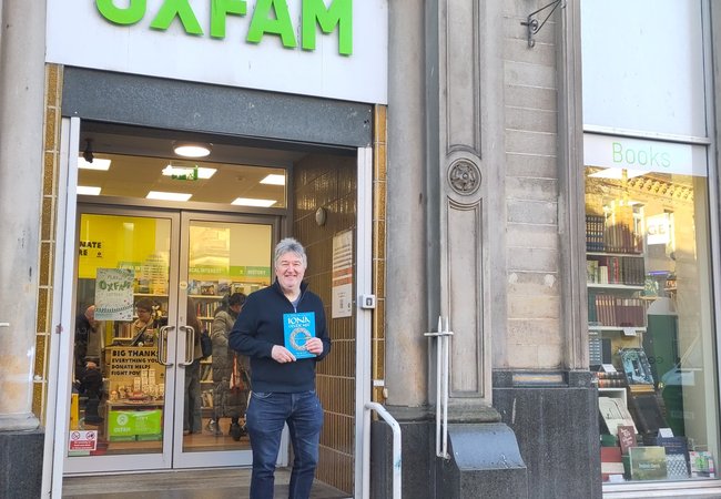 Paul Dixon holding Iona Celtic Art book on the steps of Oxfam Stirling