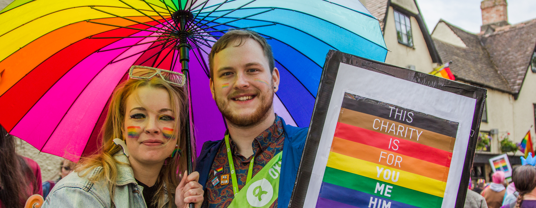 People at Pride in Oxford standing under a rainbow umbrella