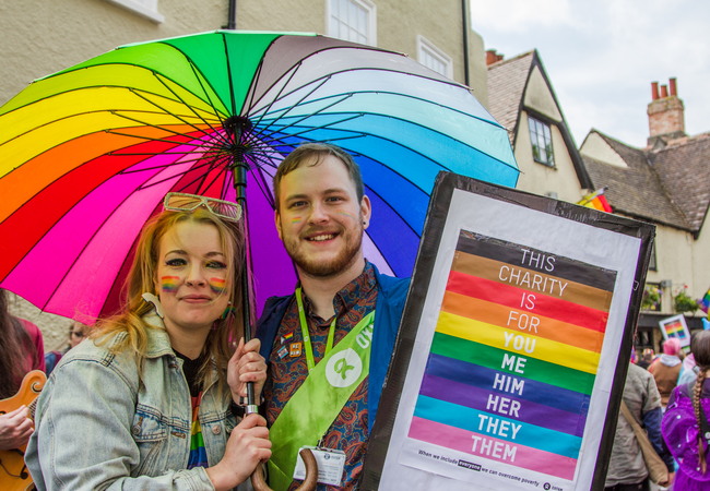 People at Pride in Oxford standing under a rainbow umbrella