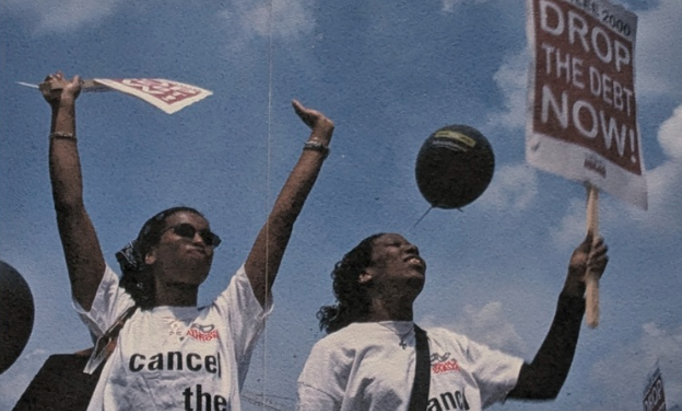 Protestors holding placards reading "Drop the debt now!"
