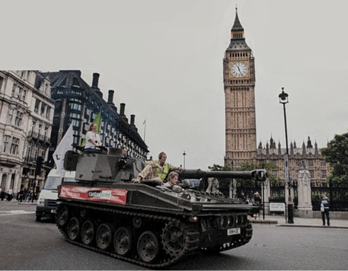 A tank being driven through central London with a banner for Oxfam's Control Arms campaign on the side.