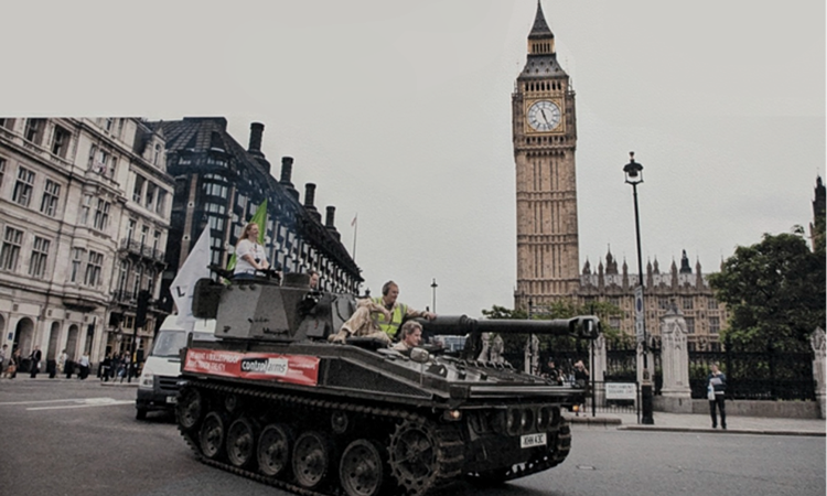 A tank being driven through central London with a banner for Oxfam's Control Arms campaign on the side.
