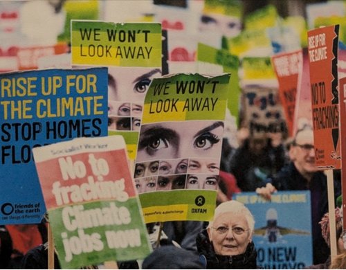 A procession of campaigns holding placards reading "We won't look away" and "Rise up for the climate"