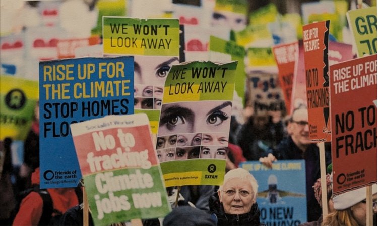 A procession of campaigns holding placards reading "We won't look away" and "Rise up for the climate"