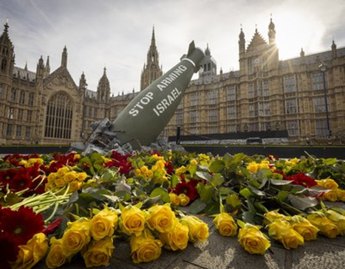 A model of a large missile with the words 'Stop arming Israel' surrounded by flowers outside the House of Commons.