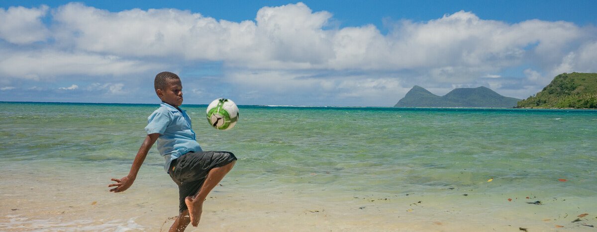 Sea-level rise: a boy in Vanuatu juggles a ball where there was once a playing field.