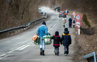 A family walk along a road with luggage in the cold. Peter Lazar/ AFP via Getty Images