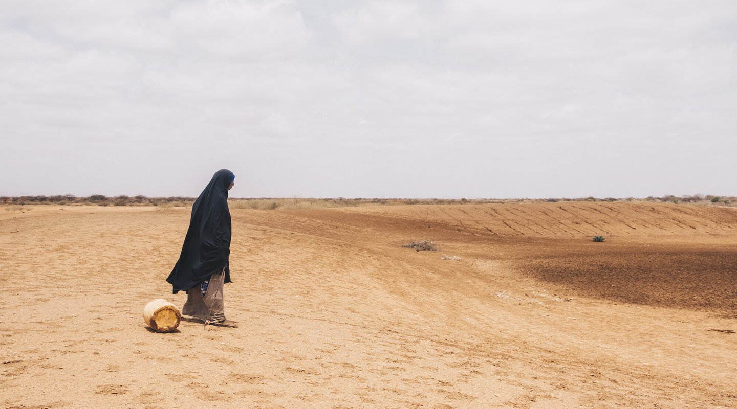 Diyaara stands before a dried water hole in Wajir County, Kenya.