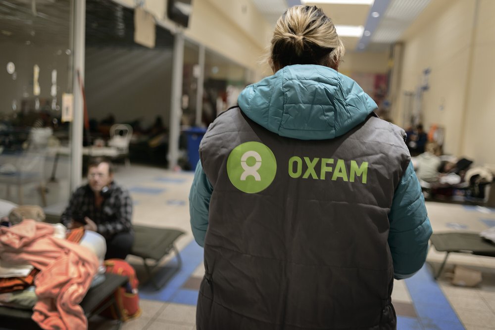 Michelle is seen from the back wearing a gilet with an Oxfam logo on.