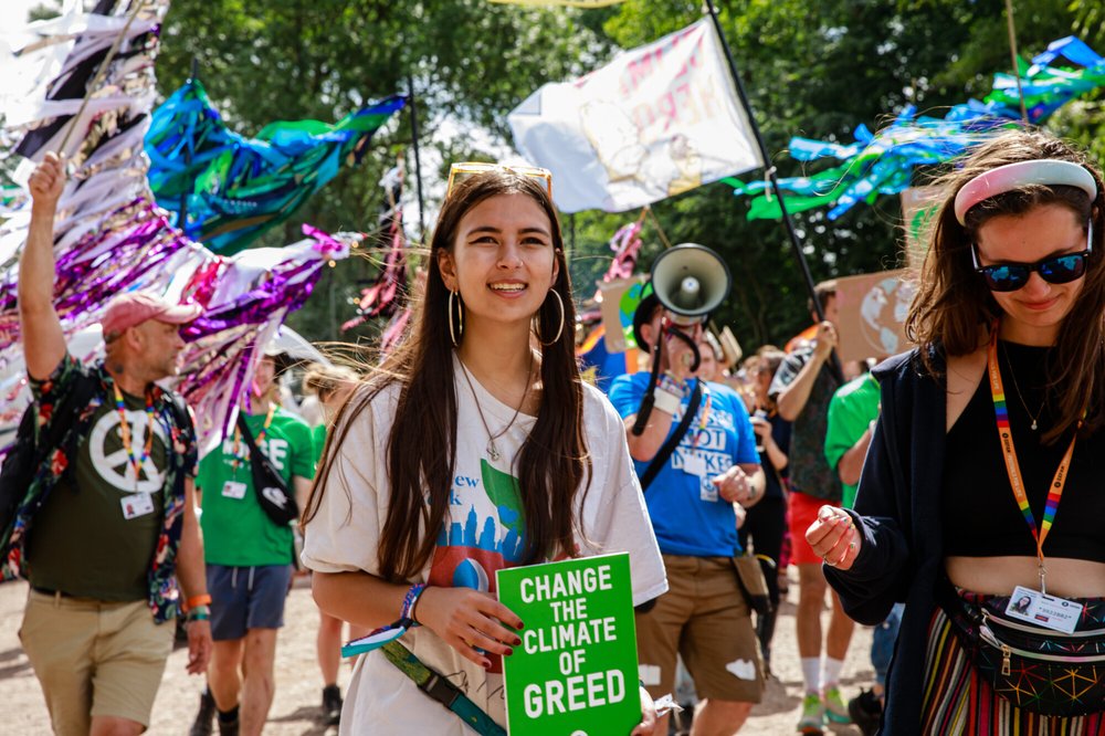 Mya-Rose Craig stands in a crowd holding a sign that says change the climate of greed.