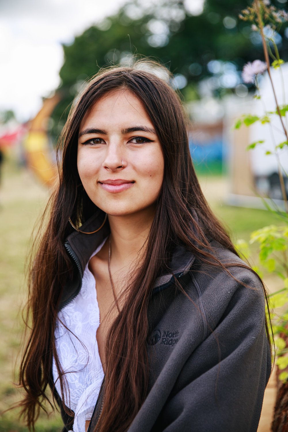 19-year-old British-Bangladeshi Mya-Rose who has long straight hair sits smiling with trees in the background