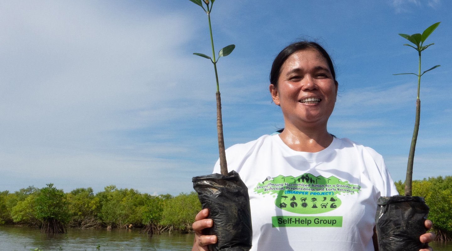 Rowena Obina, a member of a women’s group in the Philippines that undertook mangrove restoration, plants saplings.