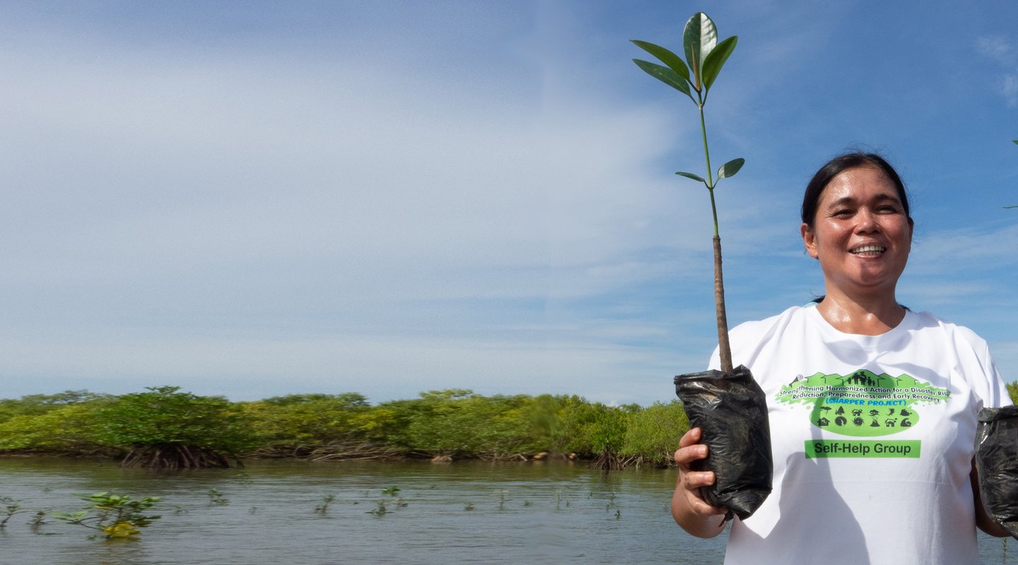 Rowena Obina, member of a women’s group in the Philippines that undertook mangrove restoration, plants saplings.