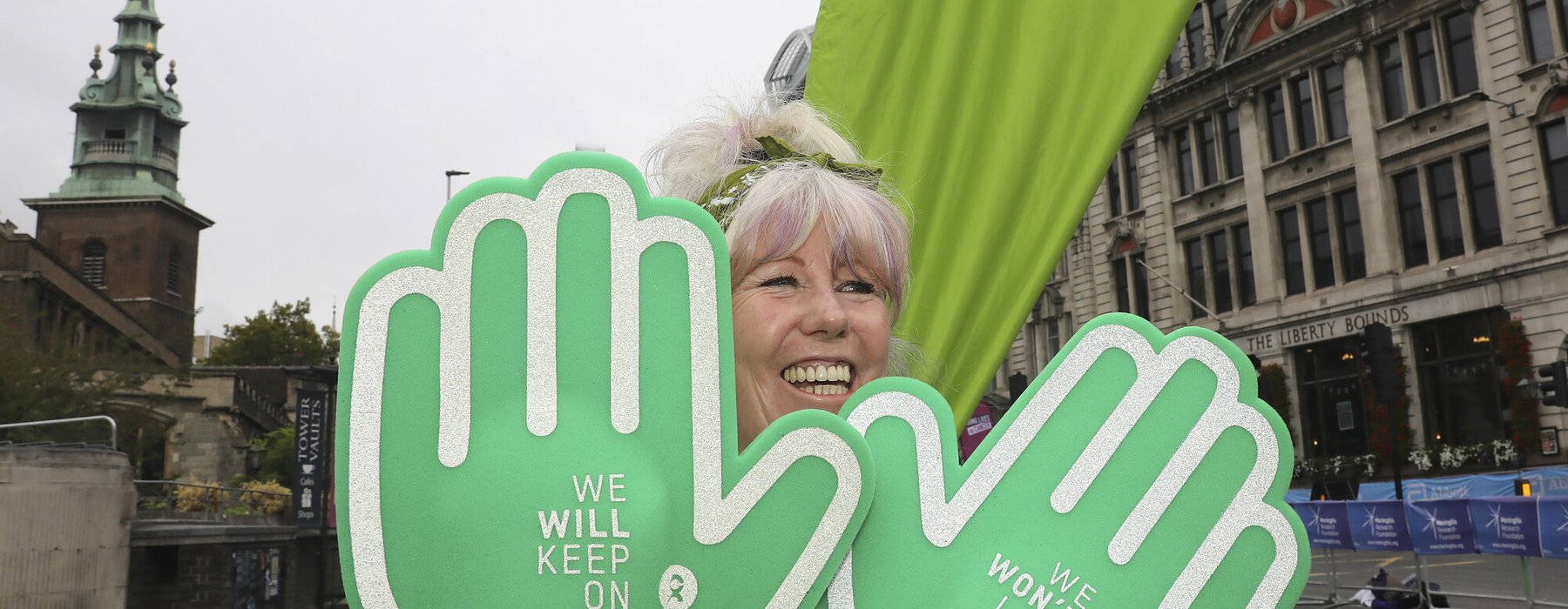 A women with huge foam hands cheering Oxfam runners at the 2023 London Marathon.