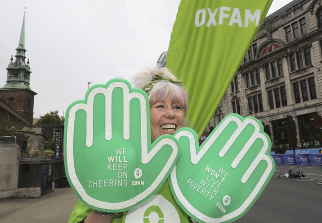 A women with huge foam hands cheering Oxfam runners at the 2023 London Marathon.