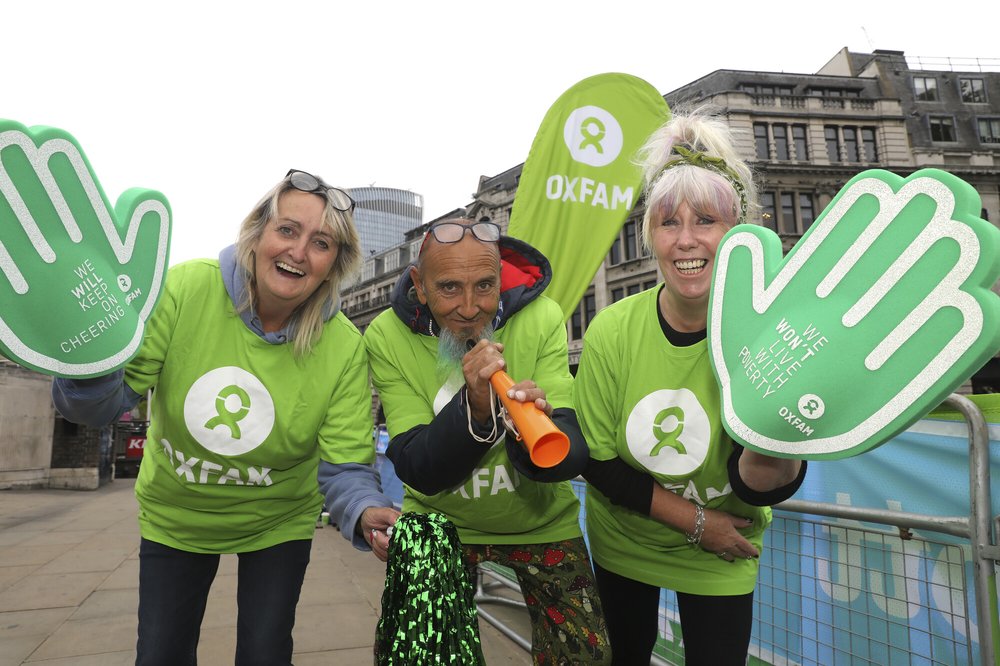 Three London Marathon volunteer supporters cheering with big foam hands.