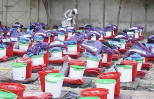 Tameer e Khalaq Foundation worker Ashraf inspecting rows of emergency kits including buckets and blankets.