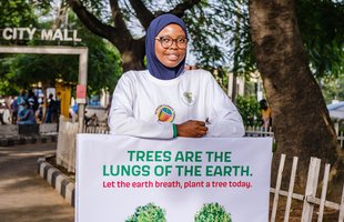 A woman in Nigeria holding a placard with lungs made of trees calling on people to plant trees as they are the lungs of the earth.