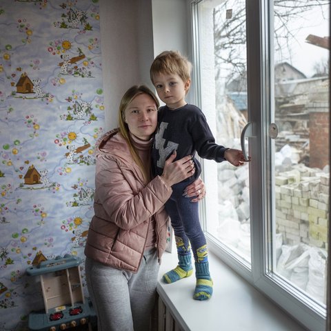 Mother and child stood by window. Image: Kieran Doherty / Oxfam