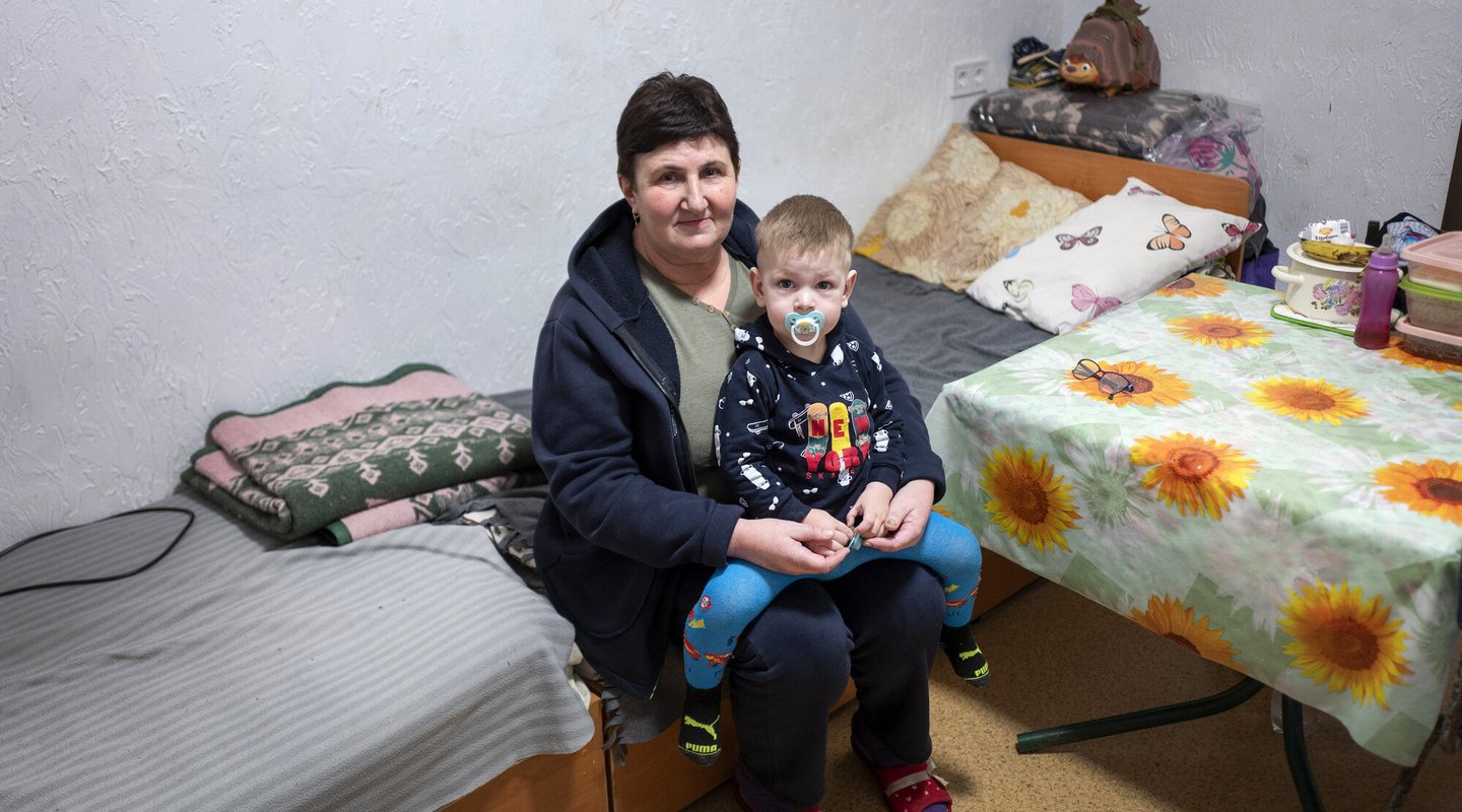 A grandmother sits with her grandson on her lap.