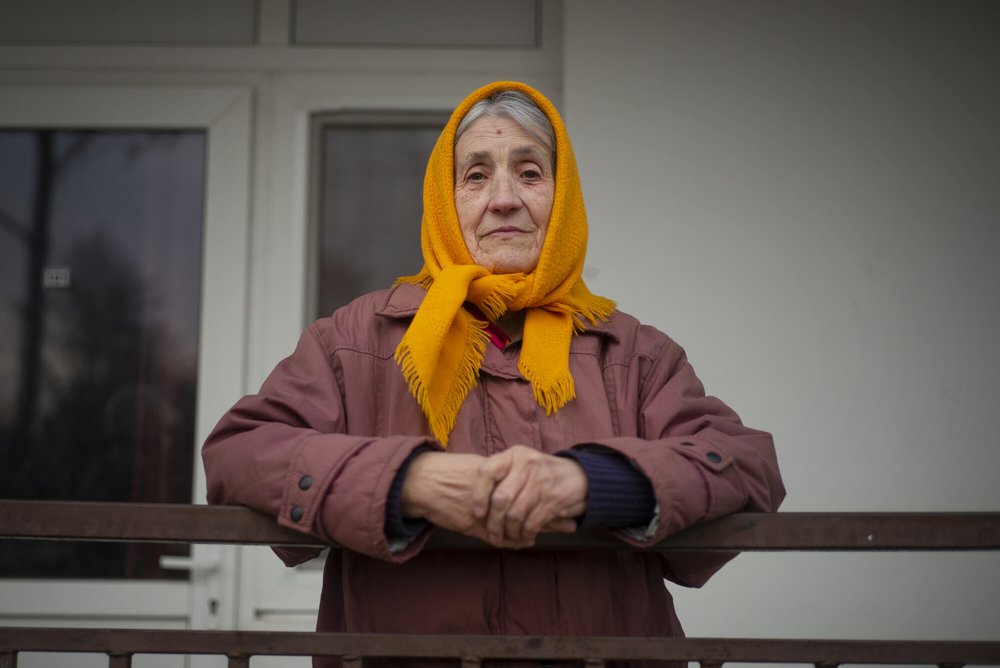 A woman stands by her house