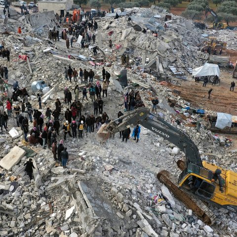 Civil defence workers and residents search through the rubble of collapsed buildings