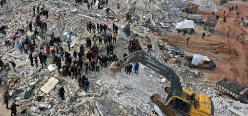 Civil defence workers and residents search through the rubble of collapsed buildings