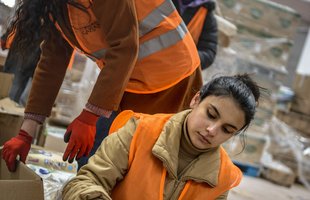 Volunteers in orange vests sort emergency distribution boxes
