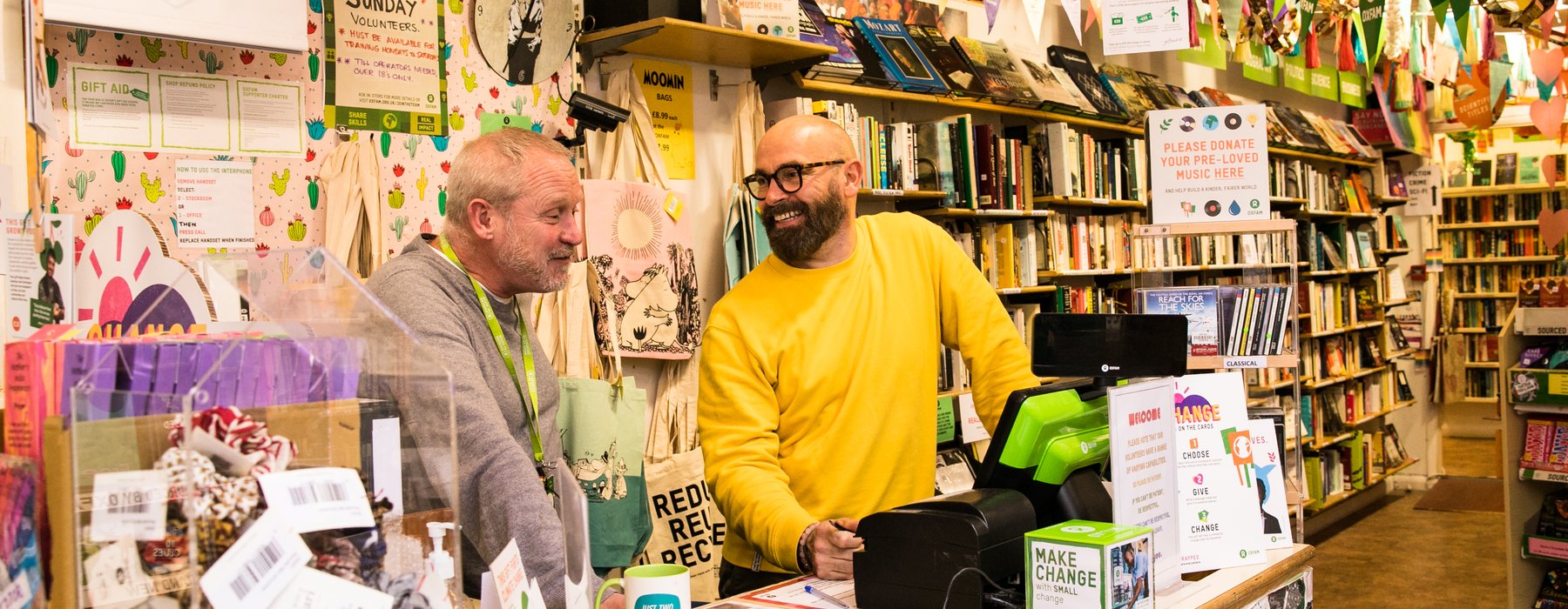 Shop Manager and Volunteer Smiling Behind colourful till