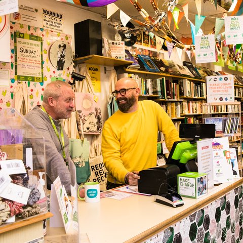 Shop Manager and Volunteer Smiling Behind colourful till